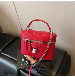 Detail of red lychee grain leather handbag with silver lock and metal chain strap