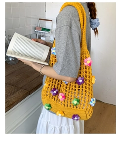 Detail of yellow crochet tote bag with colorful 3D knitted flowers and mesh pattern