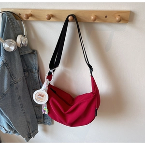 Detail of red crescent nylon crossbody bag with black strap and capybara charm