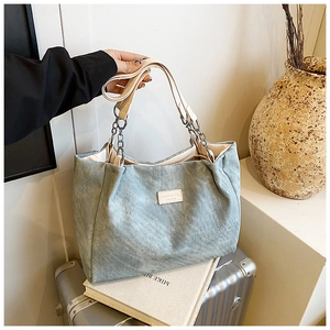 Detail of light blue corduroy tote bag featuring silver chain and white leather strap