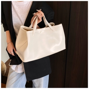 Close-up of beige tote bag with smooth synthetic leather and minimalist buckle detail