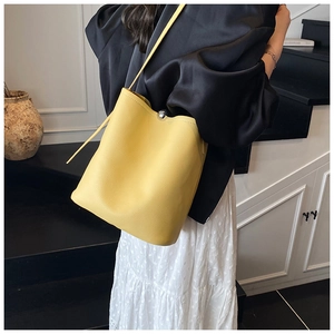 Détail d'un sac seau jaune vif en cuir grainé avec un fermoir boule en métal argenté