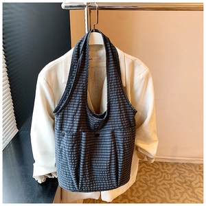 Detail of navy plaid tote bag with external buttoned pockets on a business suit