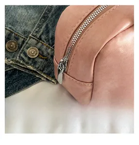 Close-up of pink PU leather bag detail with fine stitching and smooth zipper closure