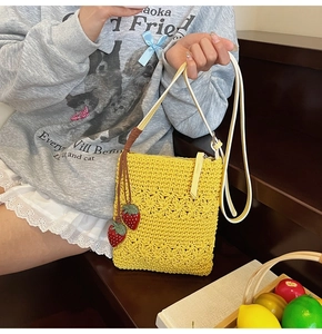 Macro view of handmade yellow crochet crossbody bag with detailed strawberry charm details