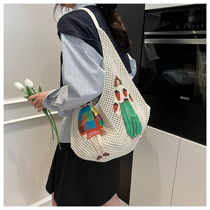 Detailed close-up of white knit tote bag featuring colorful cartoon girl embroidery