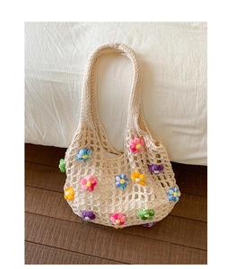 Close-up of beige crochet tote bag featuring vibrant 3D floral knit decorations