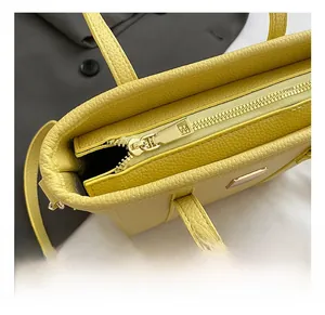 Detail view of the yellow litchi pattern leather bag with polished metal zipper closure