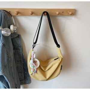 Detail of a bright yellow dumpling bag showing the side charms and adjustable strap texture