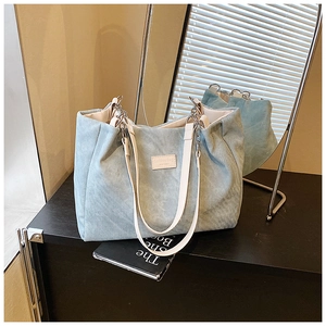 Detail of light blue corduroy tote bag with chain strap and fashion logo patch