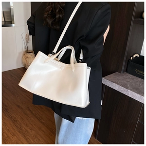 Modern white minimalist tote bag shown in a professional setting with adjustable shoulder strap