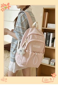 Close-up of pink nylon backpack with multi-pocket design and star plush charm detail