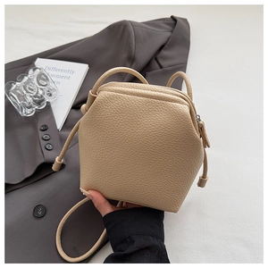 Close-up detail of cream beige lychee pattern leather crossbody bag with thin strap