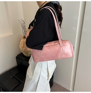 Detailed view of a pink rectangular underarm bag featuring dual straps and silver metal zipper