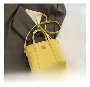 Detail showing the lychee grain texture and gold metal hardware on yellow bucket bag
