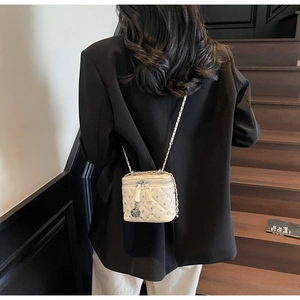Dettaglio mini borsa beige trapuntata con strass e ciondolo a forma di rosa