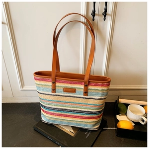 Detail of colorful rainbow striped woven tote bag with brown leather handles and logo