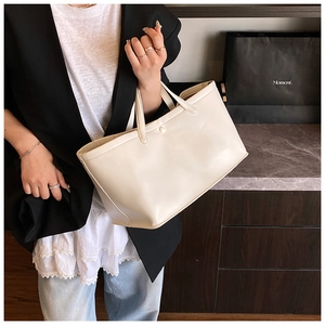 Detail of minimalist cream tote bag with elegant magnetic closure and sleek top handles