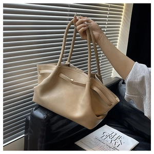 Detail view of the soft beige leather tote bag featuring unique folded structure and straps