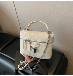 Detail of white lychee leather texture on a square crossbody bag with silver padlock