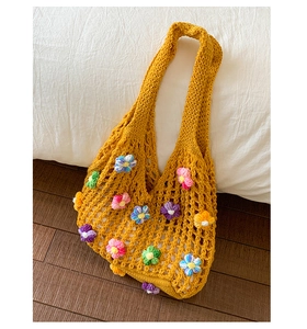 Close-up of yellow crochet tote bag with colorful 3D floral details and mesh pattern