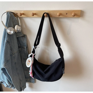 Detail of black crescent nylon crossbody bag with cute Capybara charm and wide strap