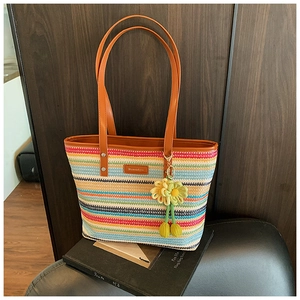 Detail of colorful striped woven beach tote bag with leather straps and floral charm