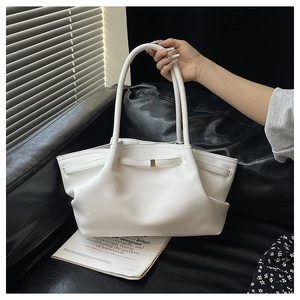 Detail of white tote bag featuring side pleats, gold buckle, and slim dual handles