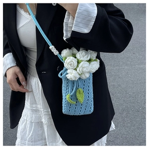 Close-up of sky blue knitted phone bag with handcrafted 3D white crochet roses