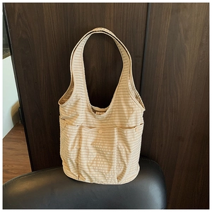Detail of striped canvas tote bag with three outer button pockets on leather seat