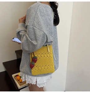 Detail of yellow knit shoulder bag featuring star textures and red strawberry charms