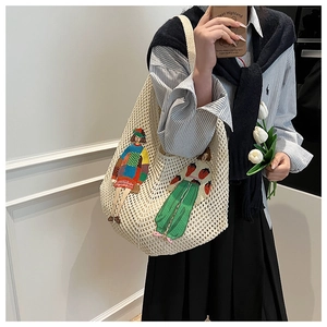 Detailed knit texture of cream shoulder bag featuring colorful cartoon girl patches