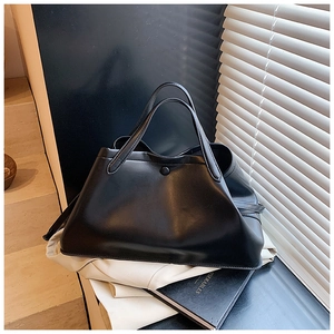 Close-up of black leather tote bag with magnetic clasp on minimalist books background