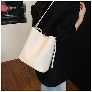 Détail du sac seau minimaliste en cuir crème avec boucle en métal argenté et texture souple