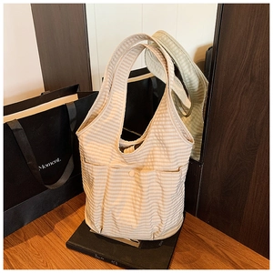 Detail of a striped canvas tote bag featuring functional outer pockets and button closure