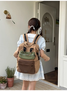 Detailed view of a multi-color canvas backpack on a person in a street setting