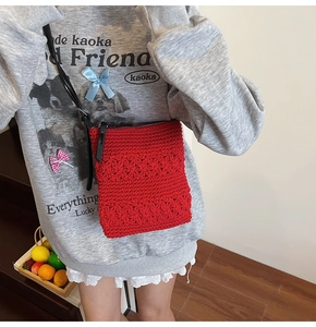 Detail of red crochet crossbody bag featuring 3D floral texture and black shoulder strap