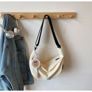 Detail of off-white dumpling canvas bag with cute capybara pendant and beaded charm