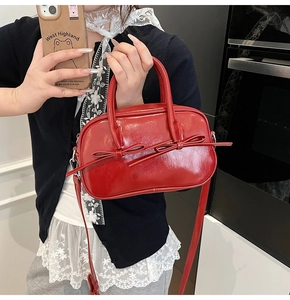 Détail du sac à main en cuir verni rouge brillant avec nœud assorti et finition