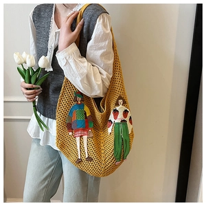 Detail of yellow knit tote bag featuring cartoon girl embroidery and handmade textures