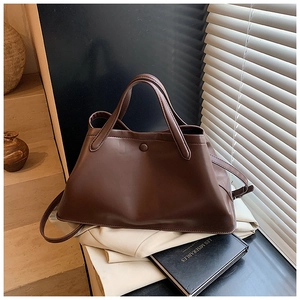 Detail of tan matte leather tote bag with sturdy top handles on a minimalist background