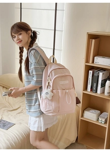 Close-up of pink nylon backpack featuring branded embroidery and white plush cloud charm