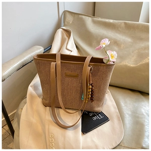 Detail of straw tote bag with leather straps and decorative wooden bead charms