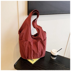 Detail of dark red checkered canvas tote bag featuring front dual pockets and button accents
