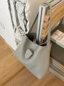 Borsa tote minimalista in pelle verde grigio chiaro con trama martellata su panca di legno