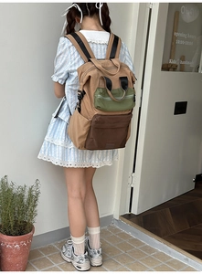 Detail of color-blocked canvas backpack with khaki and green panels and utility pockets
