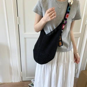 Détail du sac crochet avec bandoulière fleurie en patchwork et corps tissé noir élégant