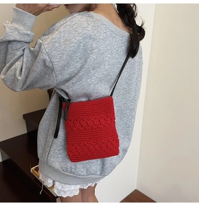 Detailed view of red crochet crossbody bag with floral texture and black strap