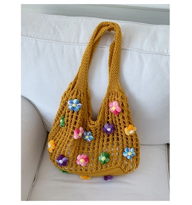 Close-up of yellow crochet tote bag featuring colorful 3D knitted flower details