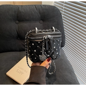 Dettaglio mini borsa nera trapuntata con strass e ciondolo a forma di camelia